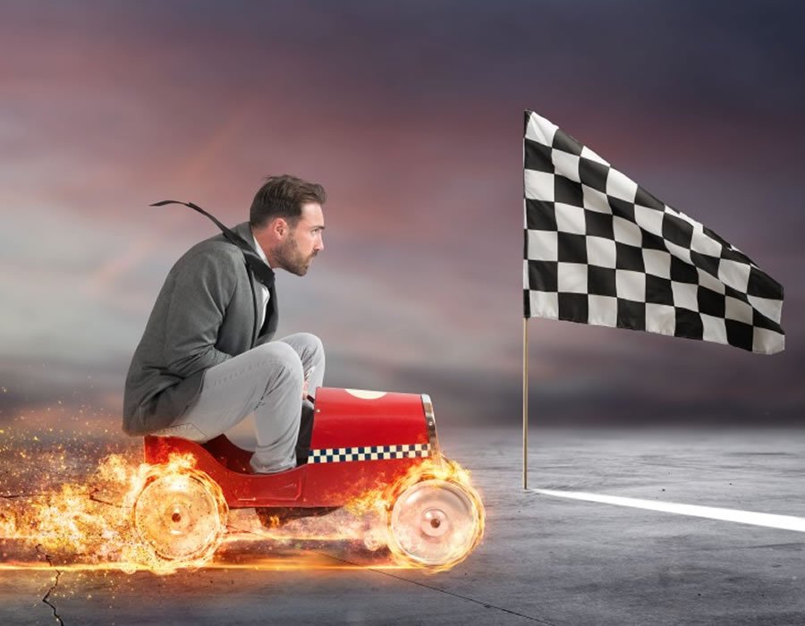 man on a small car heading towards a black and white flag
