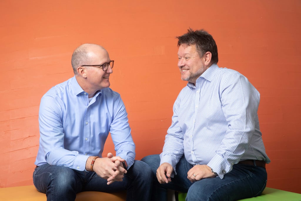 2 people sat in front of an orange wall