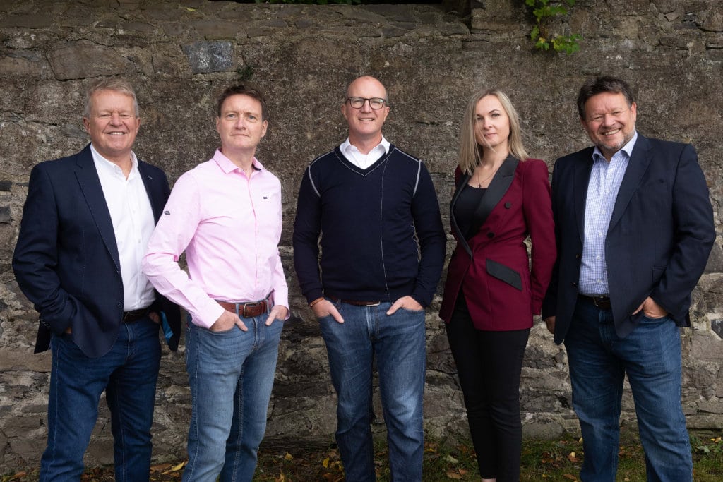 5 people standing in front of a stone wall